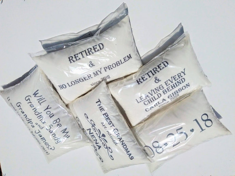 May include: Five white pillowcases with black text. The pillowcases are packaged in clear plastic bags. The text on the pillowcases reads: "Retired & No Longer My Problem since 2018", "The Best Grandmas are named Nena", "Retired & Leaving Every Child Behind Carla Gibson since 2018", "Will You Be My Grandma and Sandy? Grandpa James?", and "08-25-18".