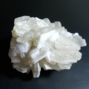 May include: A cluster of white selenite crystals, showcasing a layered, crystalline structure. The mineral formation has a soft, translucent appearance, with a slightly rough texture. The crystals are arranged in a dense, irregular pattern, creating a natural, organic form.