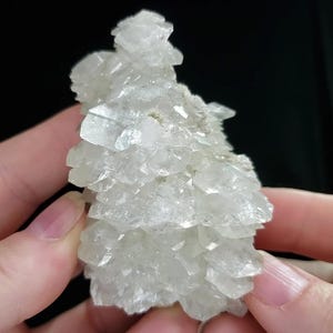 May include: A cluster of translucent, colorless crystalline mineral formations with sharp, angular edges and a jagged, multi-faceted surface texture. The specimen displays a clear, glass-like appearance with varying geometric shapes throughout the structure.