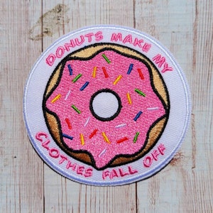 May include: White embroidered patch with a pink donut with colorful sprinkles and the text "Donuts Make My Clothes Fall Off."