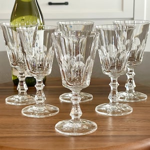 May include: Set of six clear glass wine glasses with a delicate etched design. The glasses have a tall, slender stem and a wide bowl.