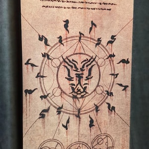 May include: A scroll with a weathered, brown paper appearance, featuring a central circular design with stylized figures and symbols. The scroll has a metal rod at the top and bottom. The text "SMOGTEETH" is visible at the bottom.