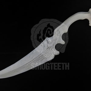 May include: A white, ornate dagger with a curved handle and a textured blade. The handle features a unique, openwork design. The text "SMOGTEETH" is visible on the blade. The dagger is set against a black background.