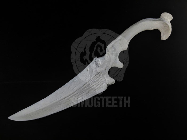 May include: A white, ornate dagger with a curved handle and a textured blade. The handle features a unique, openwork design. The text "SMOGTEETH" is visible on the blade. The dagger is set against a black background.