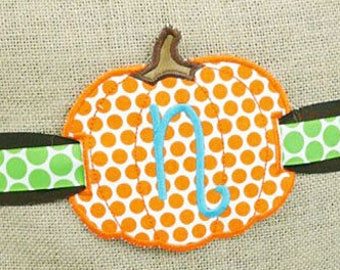 Könnte beinhalten: Ein Kissen aus Jute mit einem grün-braunen gepunkteten Band und einem Filz-Kürbis mit orange-weißen Punkten und dem Buchstaben "N" in Blau. Das Kissen ist mit Herbstblättern verziert. Der Text "Creative Appliques" ist in der rechten unteren Ecke sichtbar.