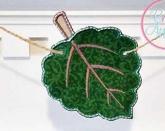 Könnte beinhalten: Ein grünes Blattbanner mit einem braunen Stiel, bestickt mit einem dekorativen Muster. Das Banner ist 4 Zoll, 5 Zoll, 6 Zoll und 7 Zoll groß. Der Text "In The Hoop Banner" und "Creative Appliques" ist auf dem Bild zu sehen.