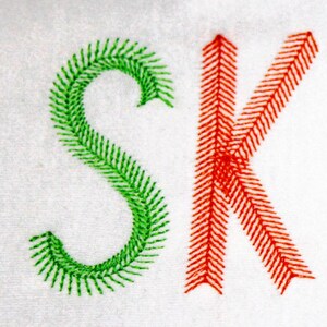 May include: The name "SKYLAR" is embroidered in a colorful font. Each letter is outlined with a different color: green, orange, blue, green, orange, blue.