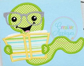 May include: Green worm wearing glasses and reading a striped book. The worm is green with a yellow belly and has a big smile. The book is yellow and white with blue stripes. The worm is sitting on a light blue background.