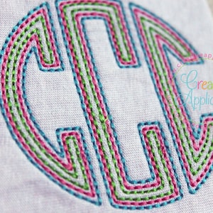 May include: A close-up of a monogram letter C embroidered in turquoise, pink, and green thread on a white fabric background.