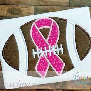 May include: A brown and white football with a pink ribbon with a pink and white checkered pattern. The ribbon is tied in a bow and the words "exclusive" are printed below the football.