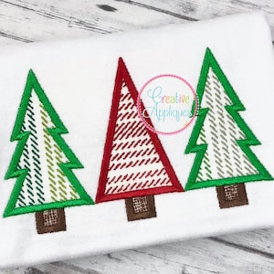 Puede incluir: Tres árboles de Navidad bordados en verde, rojo y blanco sobre un fondo de tela blanco. Los árboles están en fila y tienen un diseño simple y estilizado.