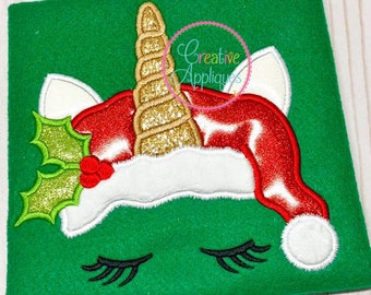 May include: Embroidered design of a unicorn wearing a Santa hat with holly and a gold horn. The unicorn has closed eyes and a white face.