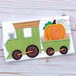May include: A green and brown train with a pumpkin in the caboose. The train is on a white background.