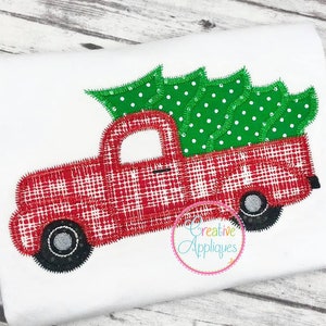 Op de afbeelding: Een rode en witte geruite pick-up truck die een groene kerstboom met witte stippen vervoert. De truck heeft zwarte wielen en een witte cabine. De afbeelding bevat de tekst "Creative Appliques".