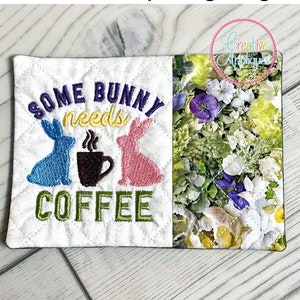 May include: A white mug rug with embroidered text that reads "Some bunny needs coffee" with two bunnies and a coffee cup. The mug rug is 5 inches by 7 inches (130mm x 180mm).