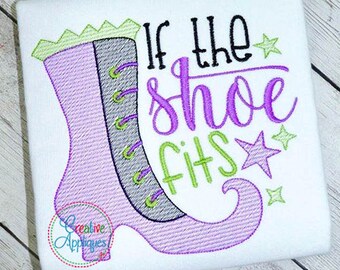 May include: Purple and green embroidered design of a witch's shoe with the text "If the shoe fits" on a white t-shirt.
