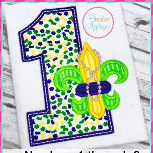 May include: A green, yellow, and purple embroidered number one with a fleur-de-lis design. The number is outlined in purple and the fleur-de-lis is outlined in green. The text "Numbers 1 through 9" and "4 sizes: 4"/5"/6"/7"" is below the number.