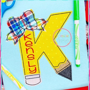 Könnte beinhalten: Ein gelber Bleistift in Form des Buchstabens K mit einer roten Schleife oben. Der Bleistift trägt den Namen "Kensly". Das Bild enthält den Text "5 Größen: 4"/5"/6"/7"/7.5"".