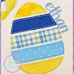May include: A yellow, blue, and white patchwork Easter egg applique with the name "Ethan" embroidered on it.