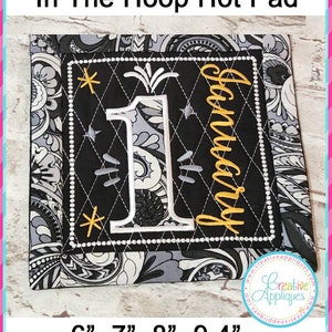 May include: A black and white quilted hot pad with a black square in the center. The square has a white number one with a gold firework design and the word "January" in gold embroidery. The hot pad is 6 inches, 7 inches, 8 inches, and 9.4 inches.