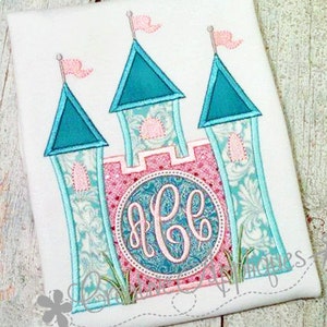 May include: Embroidered design of a pink and blue castle with a monogram in the centre. The castle has three towers with flags and a pink and white patterned design.