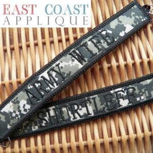 May include: Two camouflage fabric patches with black stitching. The top patch reads "Army Wife" and the bottom patch reads "Shurtleff".