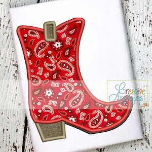May include: Red cowboy boot with a paisley pattern. The boot has a brown buckle and a brown heel.