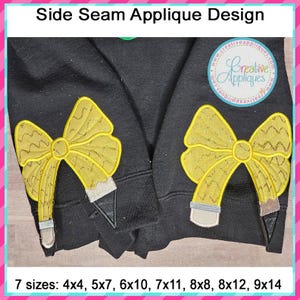May include: A black sweatshirt with two yellow bow applique designs on the side seams. The bows are shaped like pencils and have a glittery texture. The text "Side Seam Applique Design" is at the top of the image. The text "Creative Appliques" is in a circle at the top right of the image. The text "7 sizes: 4x4, 5x7, 6x10, 7x11, 8x8, 8x12, 9x14" is at the bottom of the image.