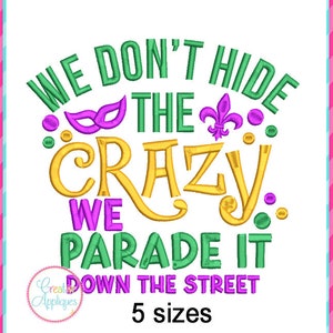 Puede incluir: Diseño bordado con el texto "We don't hide the crazy, we parade it down the street" en letras verdes, amarillas, moradas y doradas. El diseño también incluye una máscara morada y dorada y una flor de lis dorada.