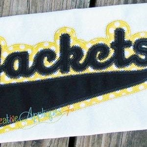 May include: A black and yellow applique with the word "Jackets" in a bold, cursive font. The applique is on a white fabric background.