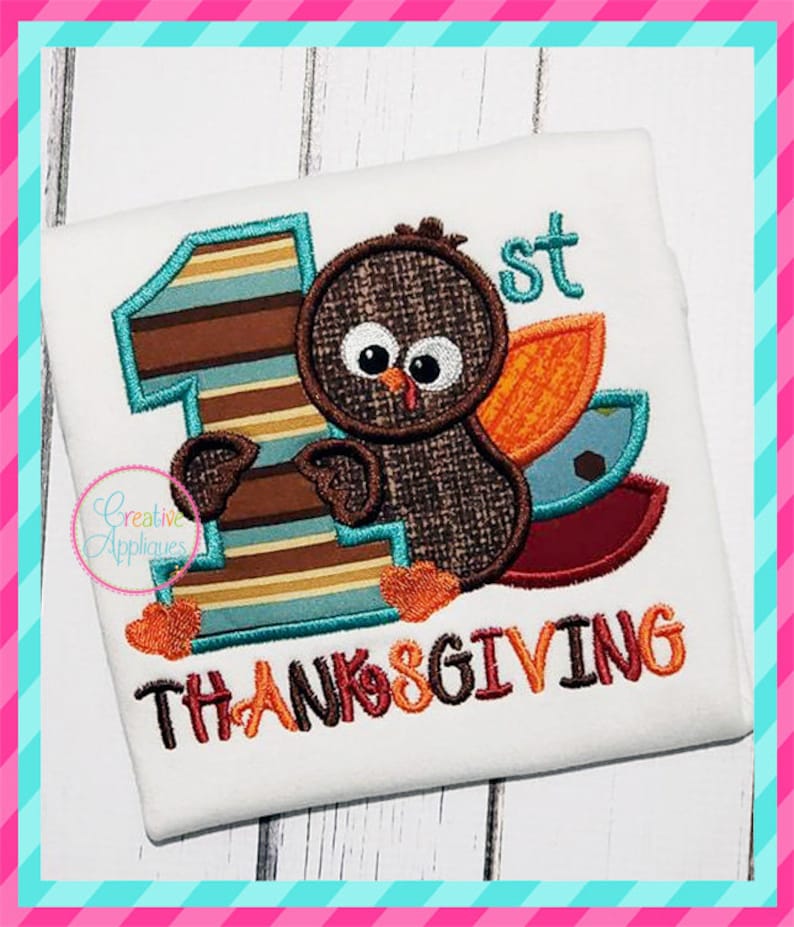 May include: A white onesie with a brown, orange, and blue turkey applique. The turkey is holding a large blue and brown number one. The text "1st" and "THANKSGIVING" is embroidered in brown, orange, and yellow thread.
