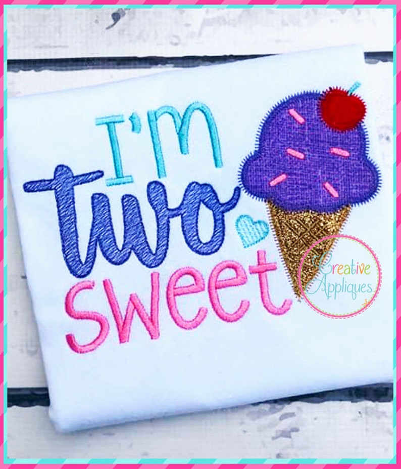May include: Embroidered design on a white t-shirt featuring an ice cream cone with sprinkles and a cherry on top. The text "I'm two sweet" is embroidered in blue, pink, and turquoise.