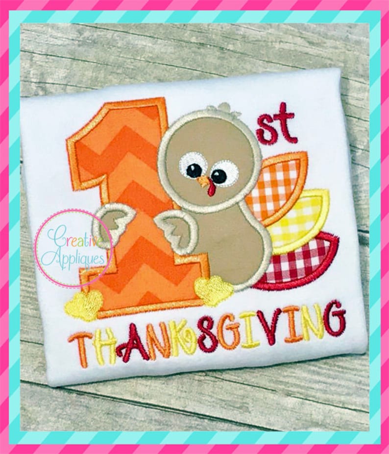 May include: Embroidered design of a turkey with a number one and the word "Thanksgiving" on a white t-shirt.