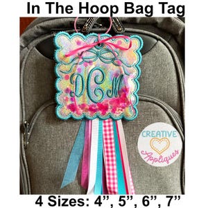 May include: A personalized bag tag with the initials DCM, featuring a square design with a scalloped edge and colorful ribbons. The tag is embellished with pink and teal accents and includes the text "In The Hoop Bag Tag". Available in 4 sizes: 4", 5", 6", 7".