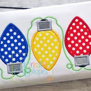 May include: Three embroidered Christmas light bulbs with polka dot patterns. The bulbs are red, yellow, and blue.