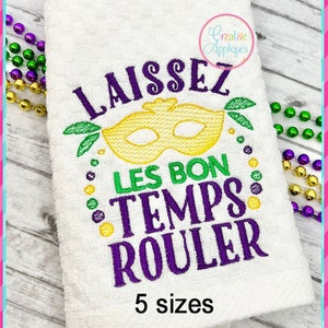 May include: White embroidered towel with the phrase "Laissez Les Bon Temps Rouler" in purple, green, and yellow. A yellow mask design is centered above the phrase. The towel is decorated with green, purple, and yellow beads. The text "5 sizes" is at the bottom.