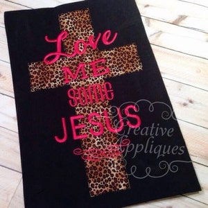 May include: Black fabric with a leopard print cross and the words "Love Me Some Jesus" embroidered in pink.