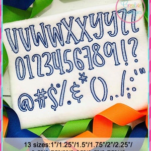 May include: A white fabric with blue embroidered letters, numbers, and symbols. The letters are uppercase and include V, W, X, Y, Z. The numbers are 0 through 9. The symbols include @, #, $, %, &, *, (, ), ., /, :, and !. The text "13 sizes: 1"/1.25"/1.5"/1.75"/2"/2.25"/ 2.5"/2.75"/3"/3.25"/3.5"/3.75"/4" is printed below the embroidered letters, numbers, and symbols.