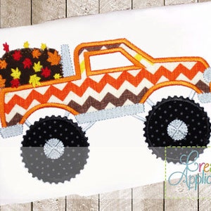 Peut inclure: Un camion monstre orange et marron avec un motif en chevron transporte un tas de feuilles d'automne dans sa benne. Le camion a de gros pneus noirs avec des jantes blanches.