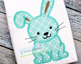 May include: White fabric with a turquoise and brown bunny design. The bunny has a geometric pattern, black whiskers, and is outlined in turquoise. The text "Creative Appliques" is visible.
