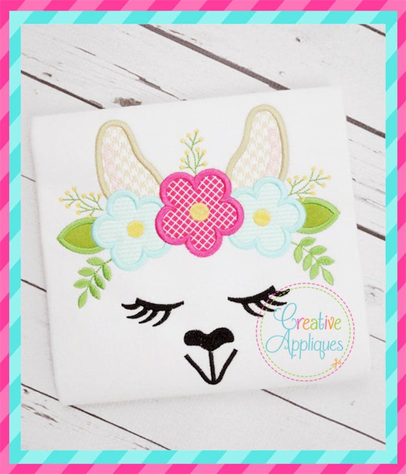 May include: Embroidered design of a llama face with closed eyes, a black nose, and a flower crown. The crown features pink, blue, and white flowers with green leaves.