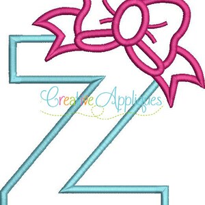 Könnte beinhalten: Ein hellblauer Buchstabe Z mit einer rosa Schleife oben. Die Schleife hat eine Schlaufe in der Mitte.