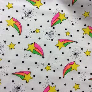 May include: White fabric with a repeating pattern of colorful shooting stars and black polka dots.