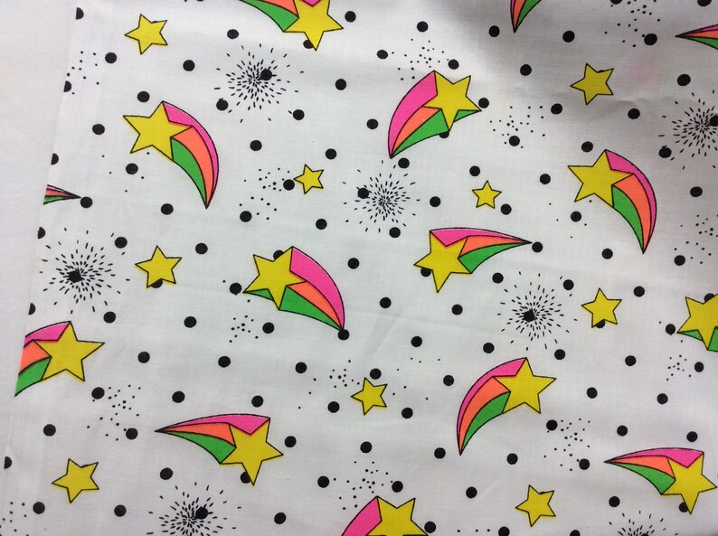 May include: White fabric with a repeating pattern of colorful shooting stars and black polka dots.