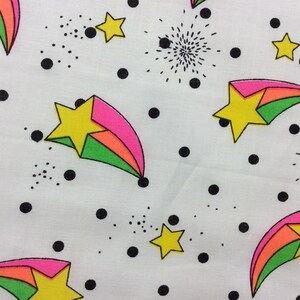 May include: White fabric with a repeating pattern of colorful shooting stars, black polka dots, and small black starbursts.