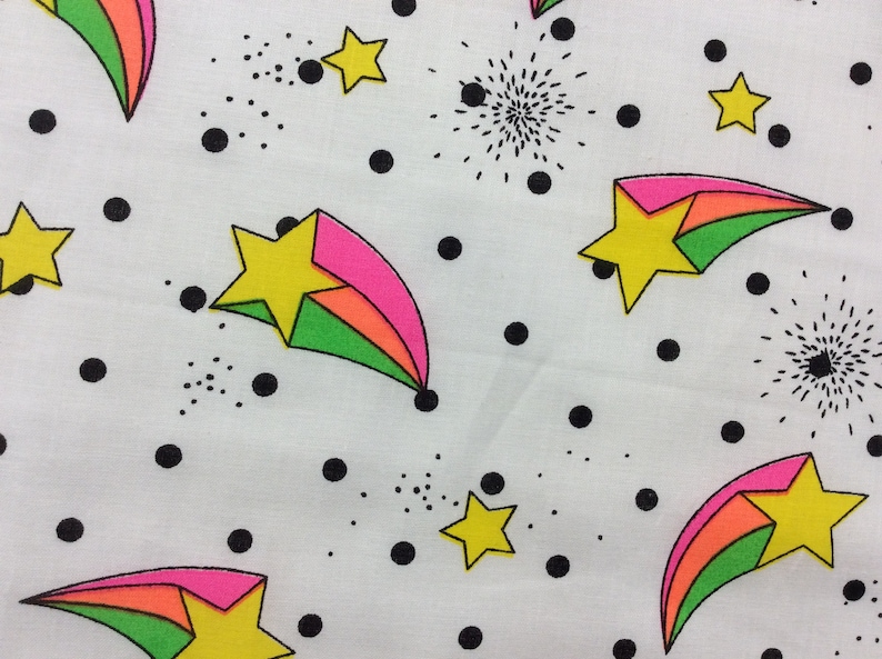 May include: White fabric with a repeating pattern of colorful shooting stars, black polka dots, and small black starbursts.