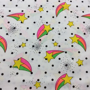 May include: White fabric with a repeating pattern of black polka dots, green, pink, and orange shooting stars with yellow stars in the center.