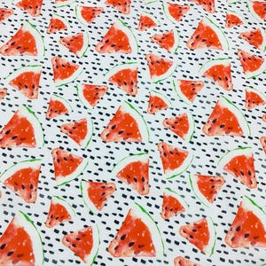 May include: White fabric with a repeating pattern of watermelon slices. The watermelons are red with black seeds and green rinds. The background has a pattern of small black dots.