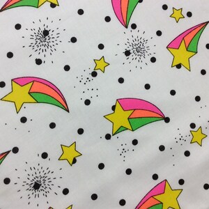 May include: White fabric with a repeating pattern of colorful shooting stars with pink, orange, and green stripes. The background is white with black polka dots.