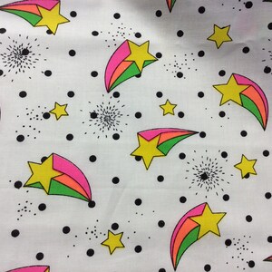 May include: White fabric with a repeating pattern of colorful shooting stars and black polka dots. The stars are yellow with pink, orange, and green stripes.